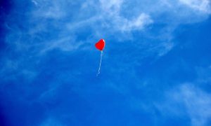 na plavom nebu crveni balon u obliku srca