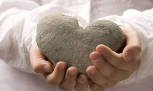 Dječje ruke drže kameno srce, predaju ga drugome