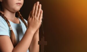 Dijete se moli, sklopljenih ruku žmireći