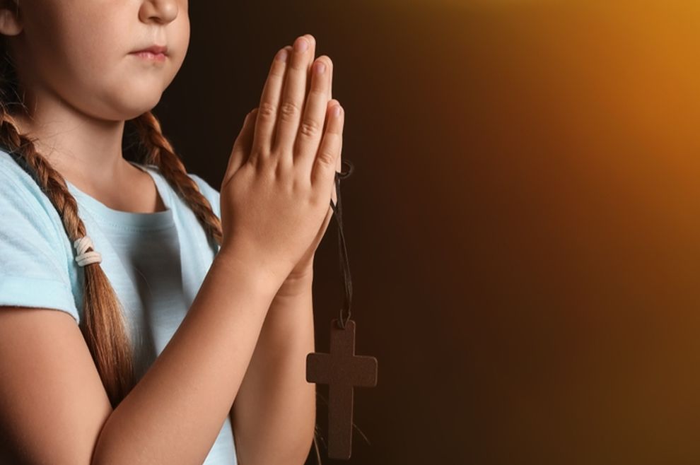Dijete se moli, sklopljenih ruku žmireći
