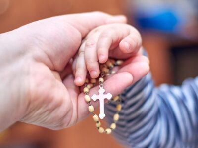 krunica_A,Small,Child,Takes,A,Rosary,From,His,Dad’s,Hand