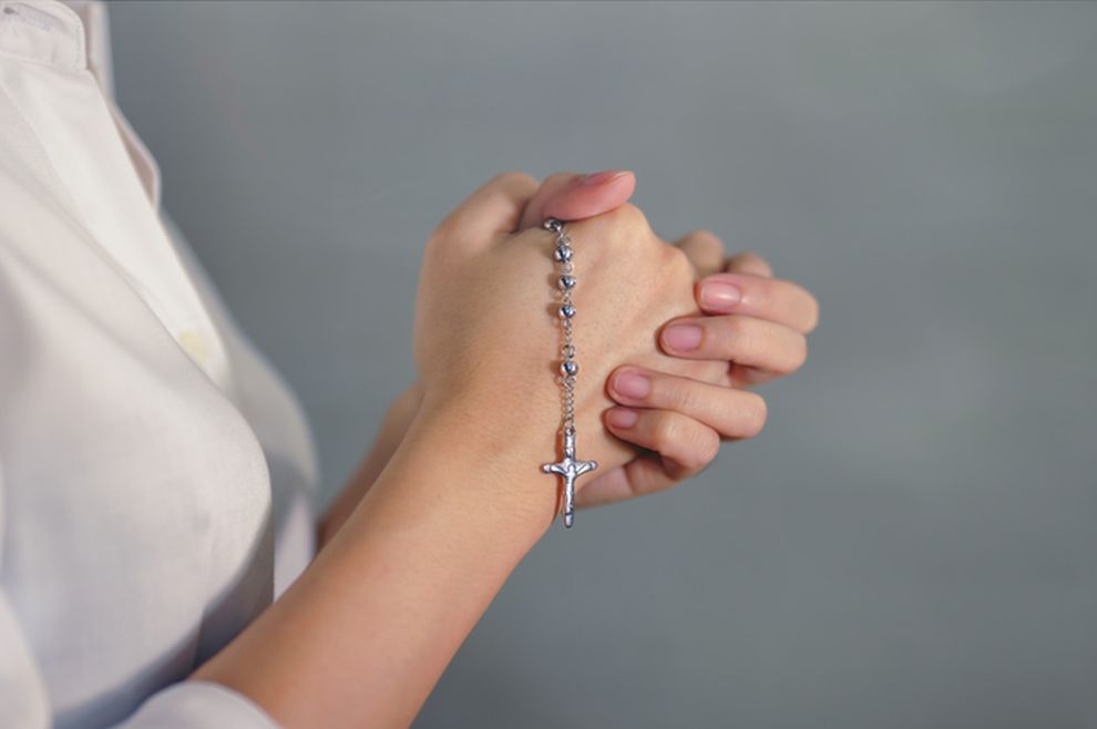Ženska osoba drži krunicu u ruci, moli se