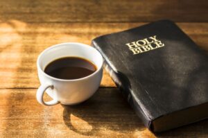 A,Cup,Of,Coffee,And,Holy,Bible,On,Wooden,Table
