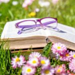 Open,Book,And,Glasses,On,The,Grass,Among,The,Blooming
