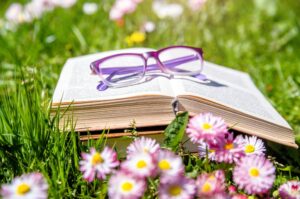 Open,Book,And,Glasses,On,The,Grass,Among,The,Blooming