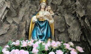 Majka Božja, spomenik s cvijećem u pozadini stijene