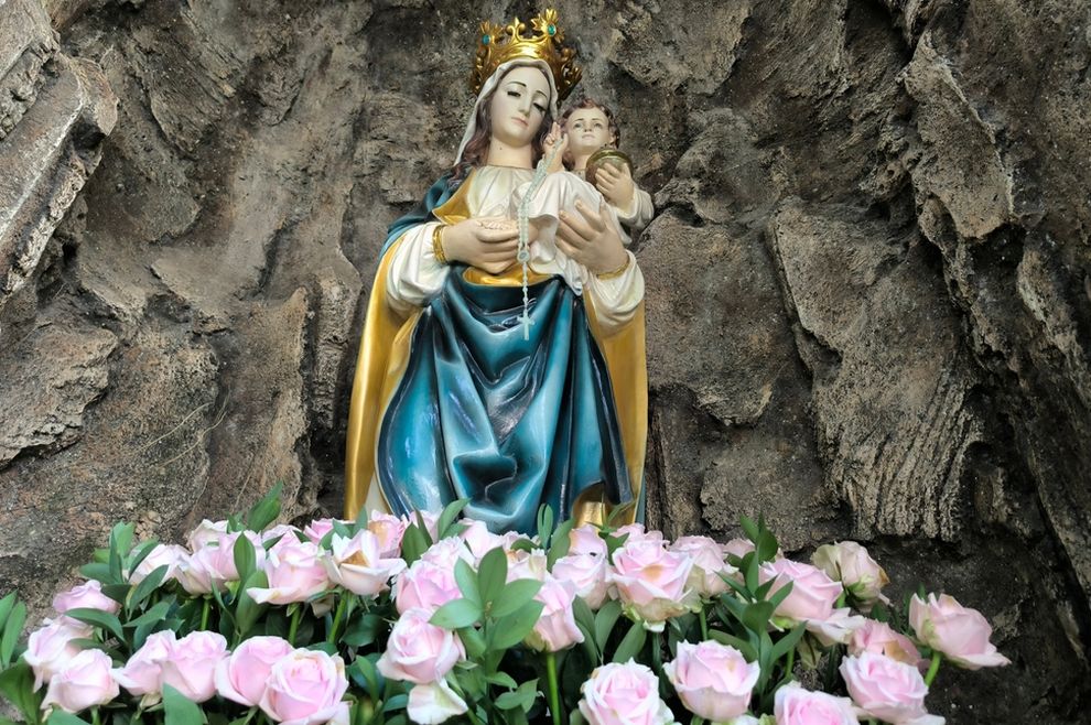 Majka Božja, spomenik s cvijećem u pozadini stijene