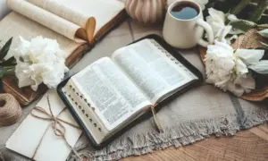 otvorena Biblija na stolu s kavom i cvijećem