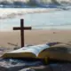 otvorena biblija i križ na plaži