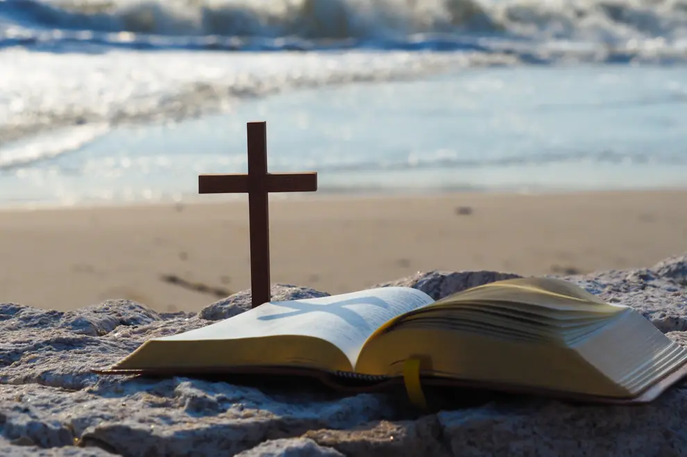 otvorena biblija i križ na plaži