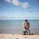 Muškarac kleči na koljenima ispred oceana, moli se