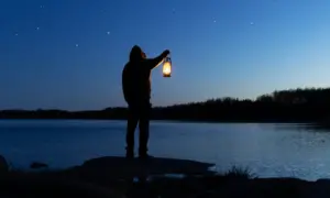 Muškarac u mraku drži lampu-s vjetlost
