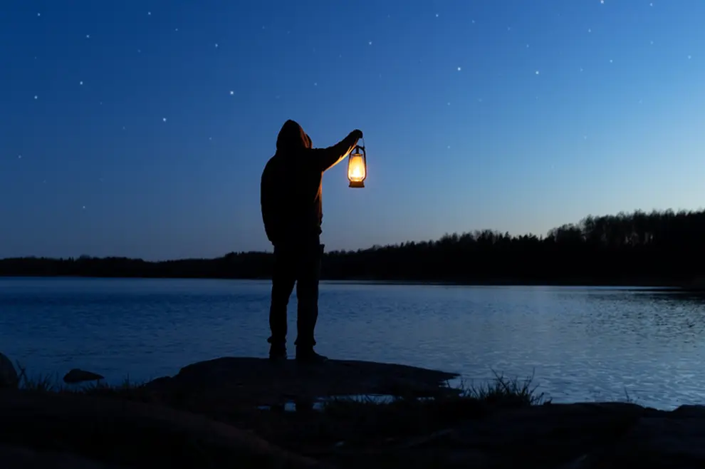 Muškarac u mraku drži lampu-s vjetlost