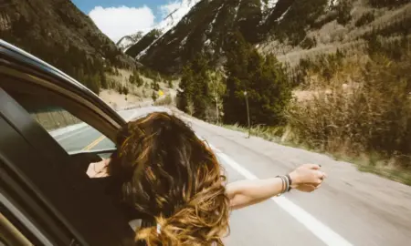 Ženska osoba se nagnula iz auta, vozi se prema planinama ljeti, sreća ilustracija