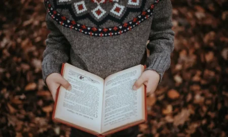 Osoba drži otvorenu knjigu dok stoji u prirodi